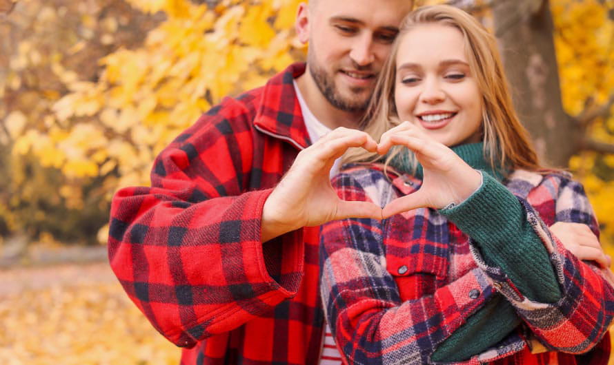 Fall couple wearing flannels heart hands