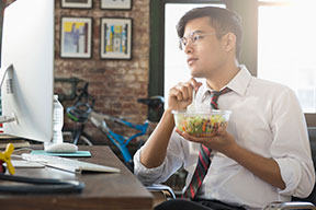 年轻人在办公桌前吃沙拉