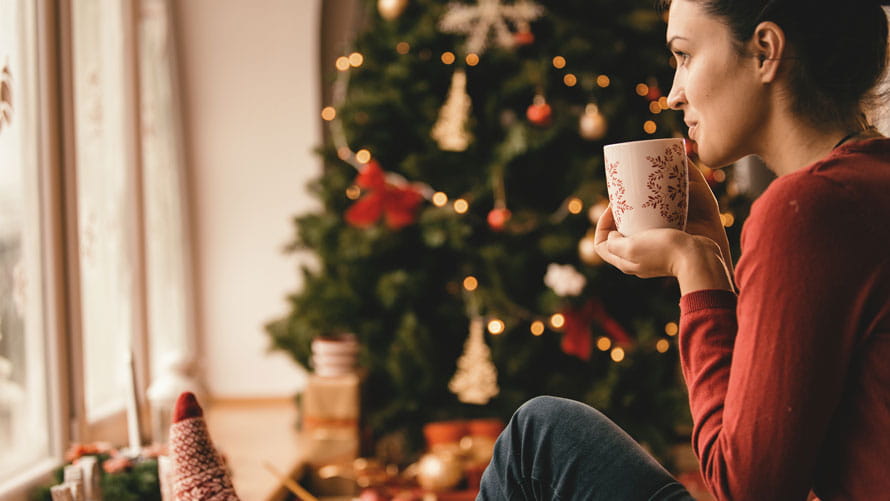 年轻女子在圣诞树旁喝茶。