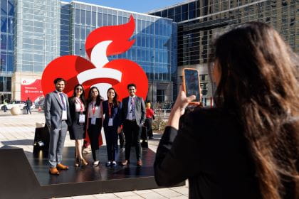 Scientific Sessions attendees taking a photo in front of the AHA Heart and Torch logo