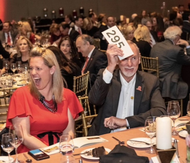 罗宾·莱利和德维恩·雷蒙(两人都坐在中间)参加了2019年塔尔萨心脏舞会的拍卖，这是他们参与美国心脏协会的众多方式之一。(美国心脏协会)