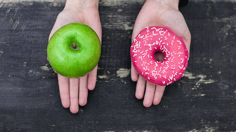 双手在苹果和甜甜圈之间做出选择