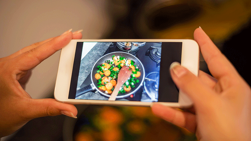 女人拿着智能手机拍摄食物