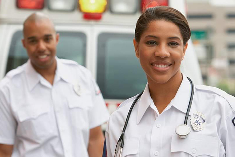 男女护理人员站在救护车后面微笑
