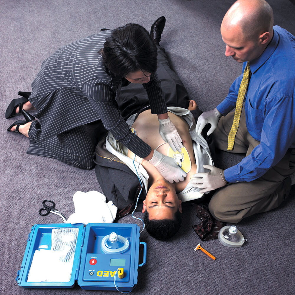 商务女性对办公室地板上的男性使用AED