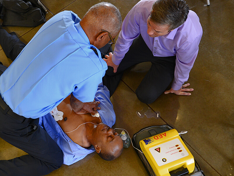 两名男子在地板上的无意识男人上表演CPR