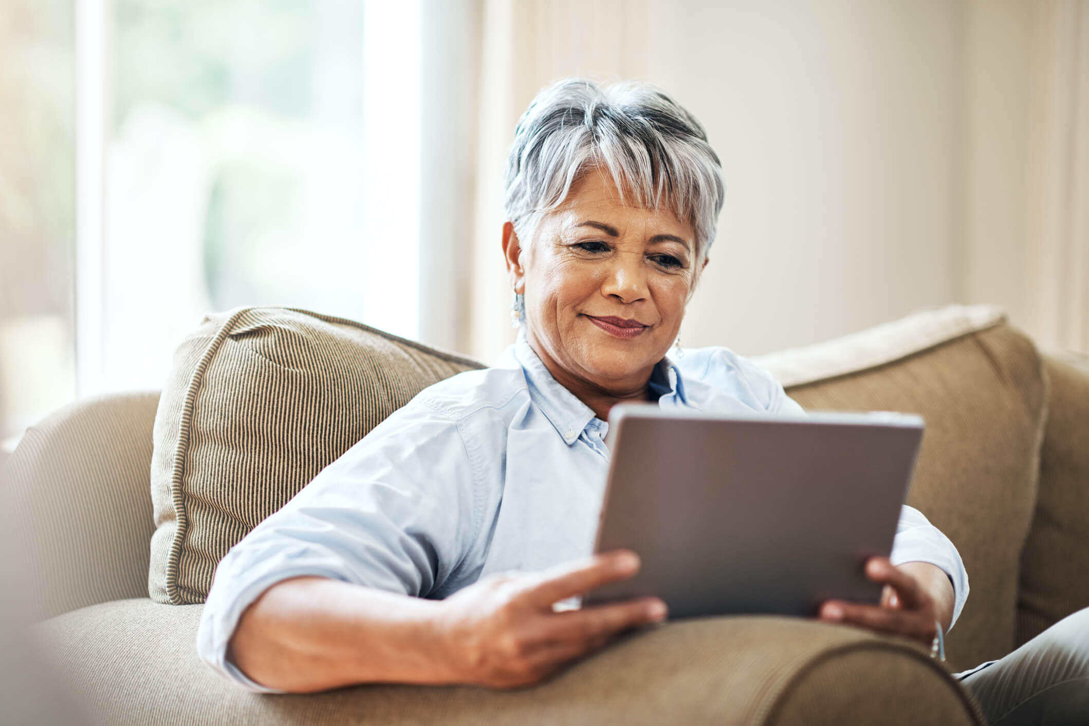 Mujer con cabello gris mirando tablet