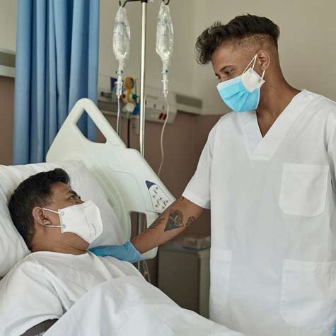 戴着面具和手套的男护士安抚躺在病床上戴着面具的男病人。