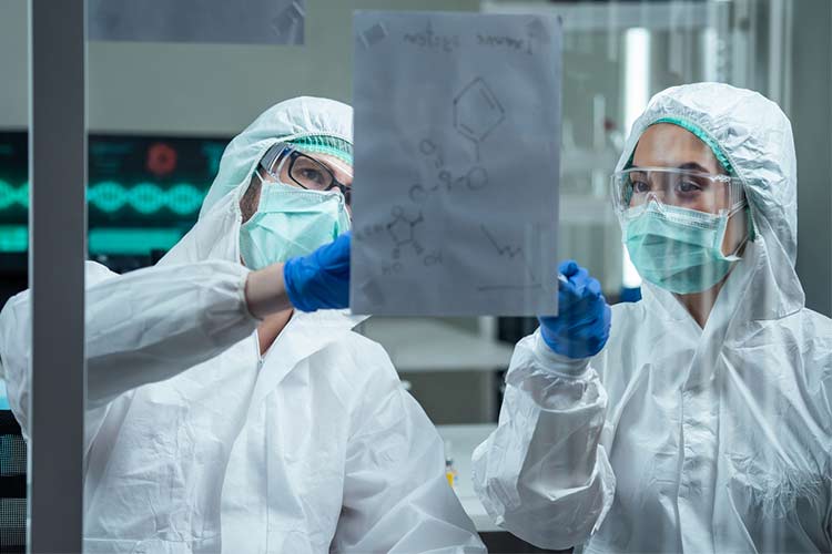 两名实验室工作人员穿着个人防护装备分析冠状病毒结构。