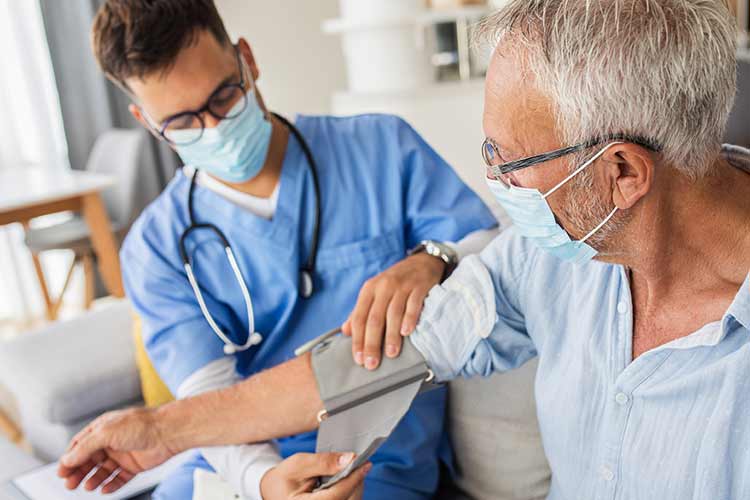 年轻男性医疗保健工作者调整在一个老男性患者的胳膊的血压袖口。