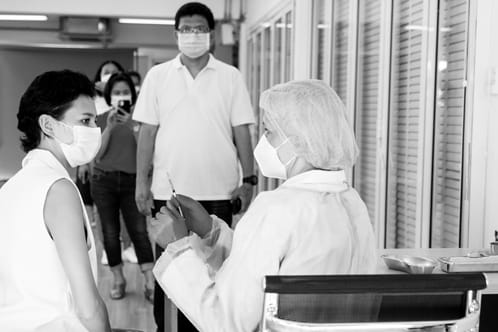 医护人员正在为等候的病人准备注射针头，看到更多的病人在排队等候轮到他们