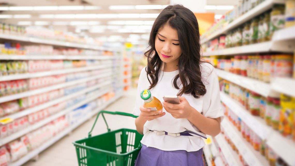 亚洲妇女使用手机查找标签上的成分