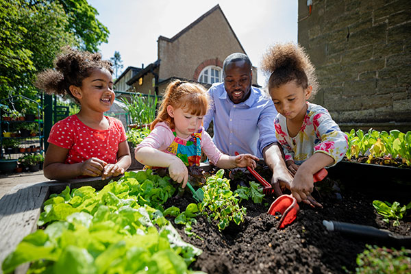 一位老师和孩子们在社区花园里种植